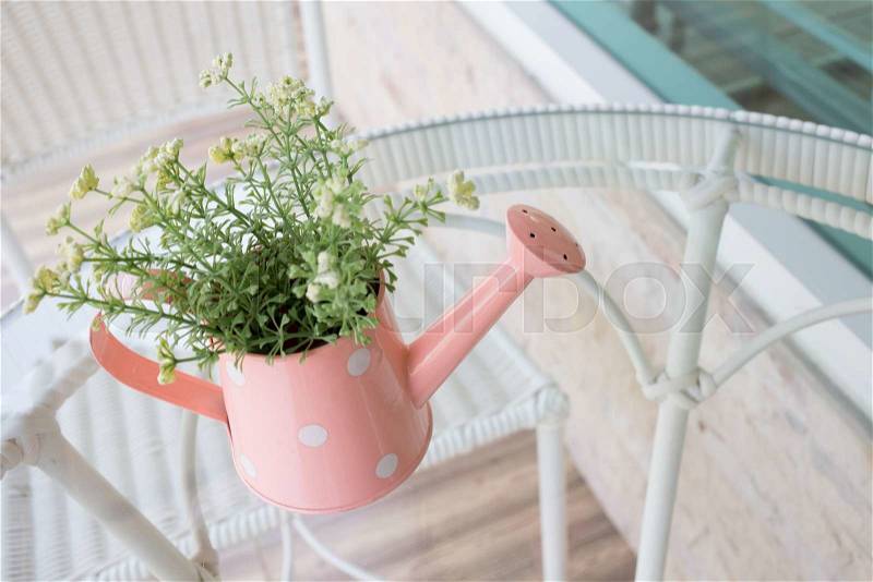 Flowers vase decorated on mirror table at living room, artificial flowers in vase watering can, stock photo