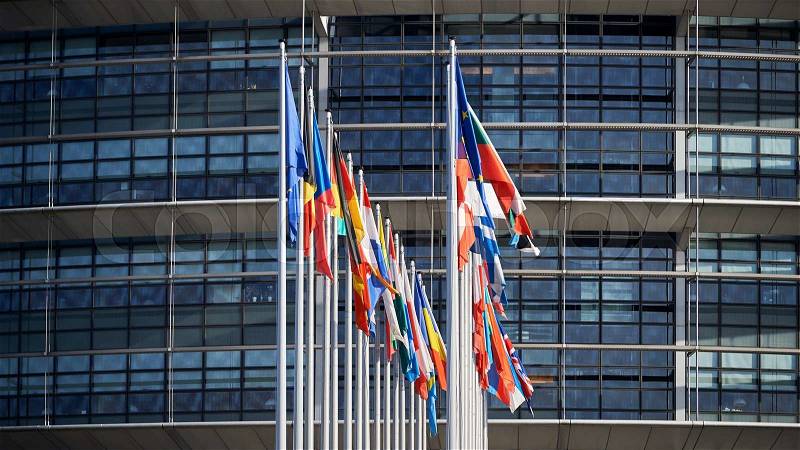 Front view of all members European Union flags waving in front of European Parliament building on a beautiful morning , stock photo