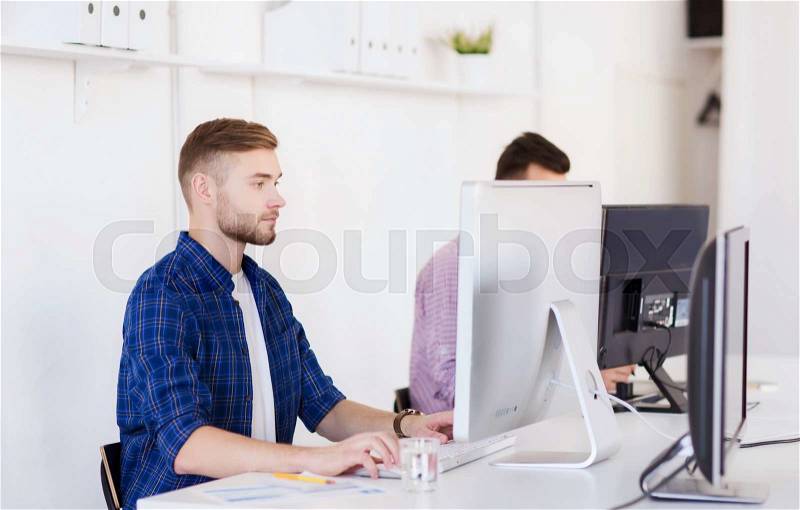 Business, technology, education and people concept - young creative man or student with computer at office, stock photo