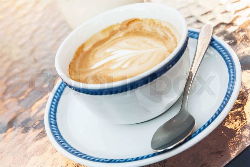 Cup of cappuccino. Coffee with milk foam stands on glass table in street cafe, closeup photo with selective focus, stock photo