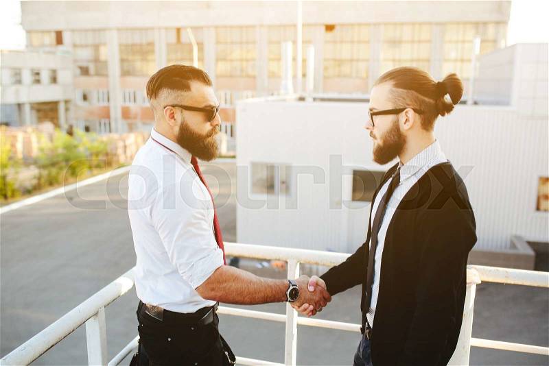 Portrait of two businessmen shaking hands, outside, stock photo
