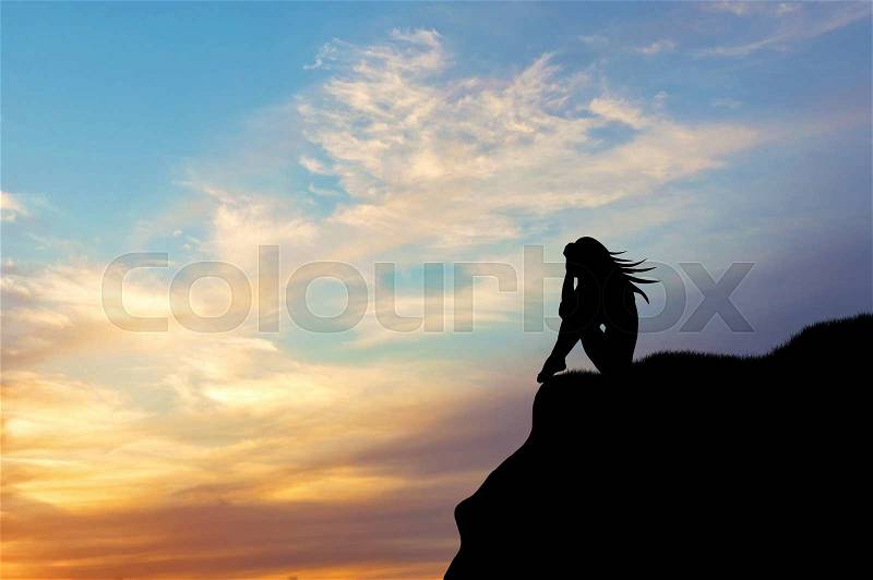 Loneliness concept. Silhouette of a woman alone on a hill at sunset, stock photo