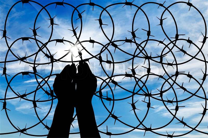 Concept of the refugees. Silhouette of a hand outstretched to the sun in the sky background barbed wire, stock photo