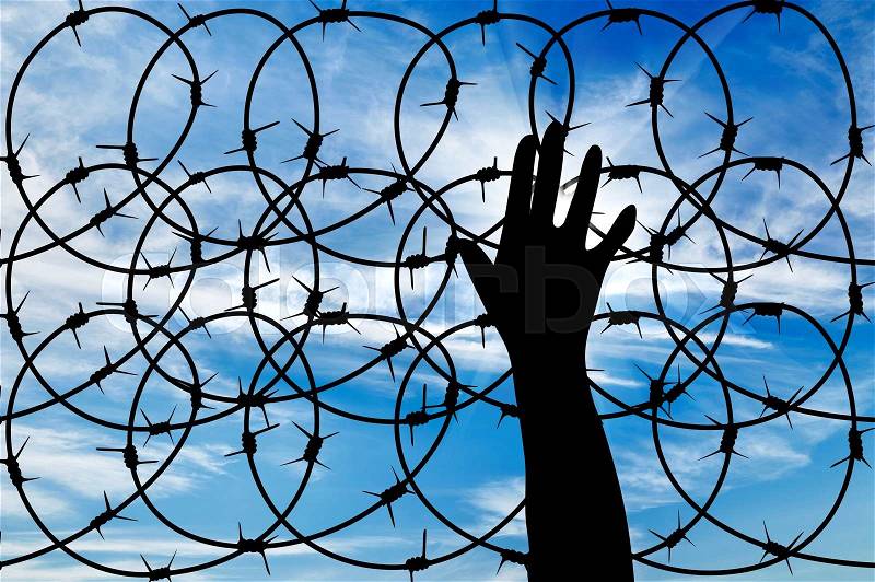 Concept of the refugees. Silhouette of a hand outstretched to the sun in the sky background barbed wire, stock photo