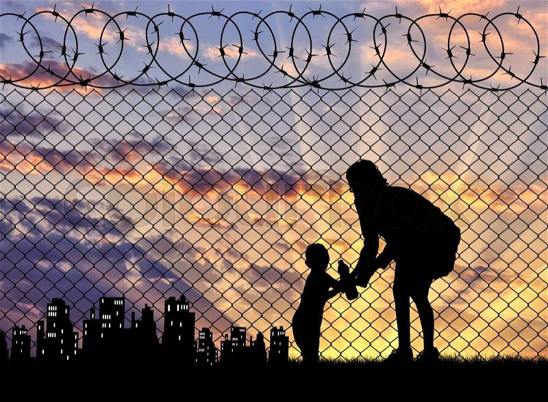 Concept of the refugees. Silhouette refugee mother with a baby in the background of the fence and the city at sunset, stock photo