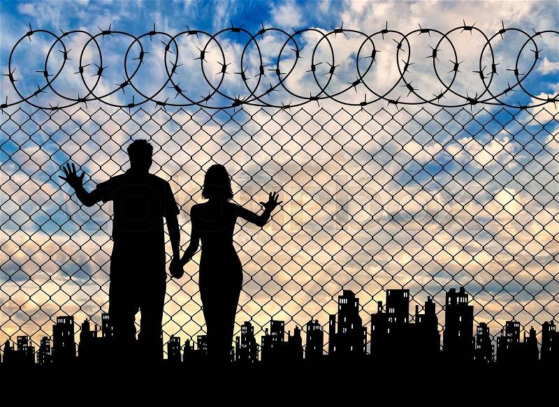 Concept of the refugees. Silhouette of refugee families near the fence on the background of the city and sunset, stock photo