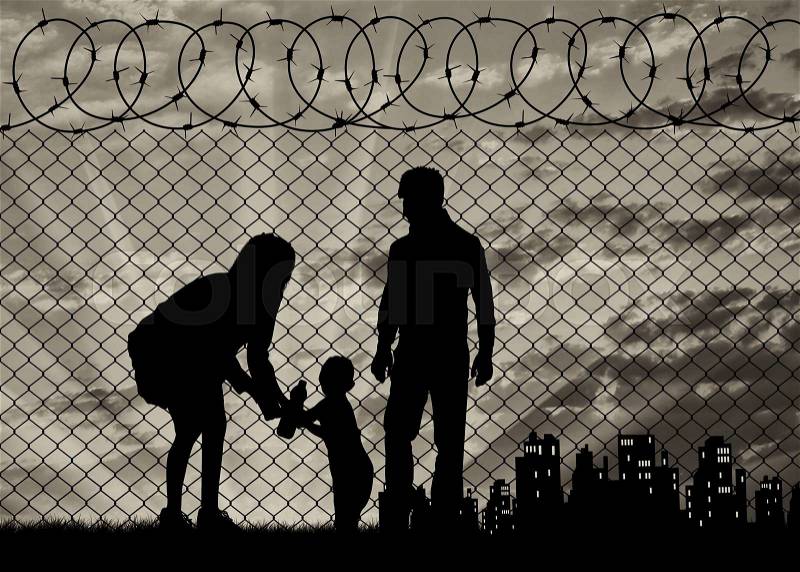 Concept of the family of refugees. Silhouette of refugee families near the fence on the border on the background of the city in the distance at sunset, stock photo