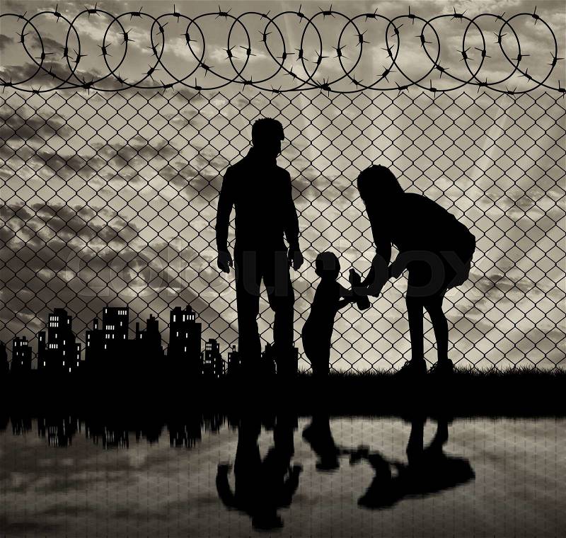 Concept of the family of refugees. Silhouette of refugee families near the fence on the border on the background of the city in the distance at sunset and reflection, stock photo