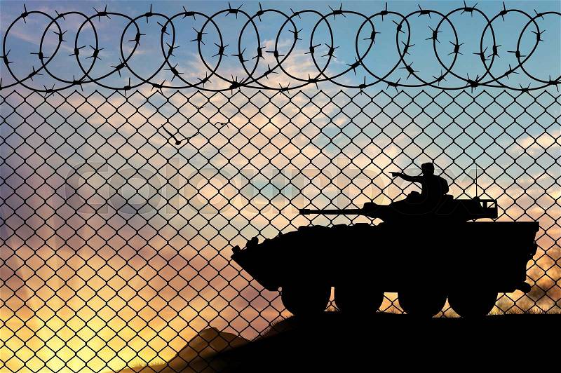 Concept of war. Silhouette Military armored personnel carrier at sunset near the fence, stock photo