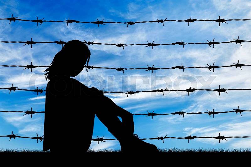 Concept of refugee. Silhouette Despair refugee woman near the fence of barbed wire, stock photo