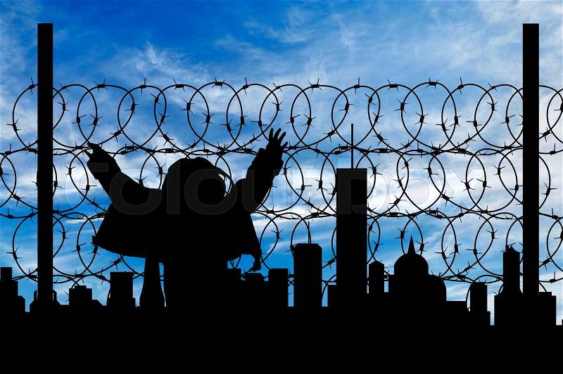 Safety concept. Silhouette of a refugee near the fence of barbed wire on the background of the city away, stock photo