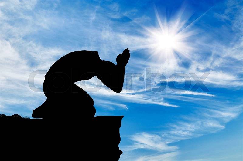 Silhouette of man praying at the top against the beautiful cloudy sky, stock photo