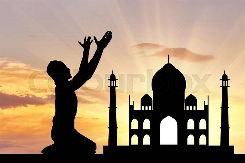Concept of religion is Islam. Silhouette of man praying at sunset, and the mosque, stock photo