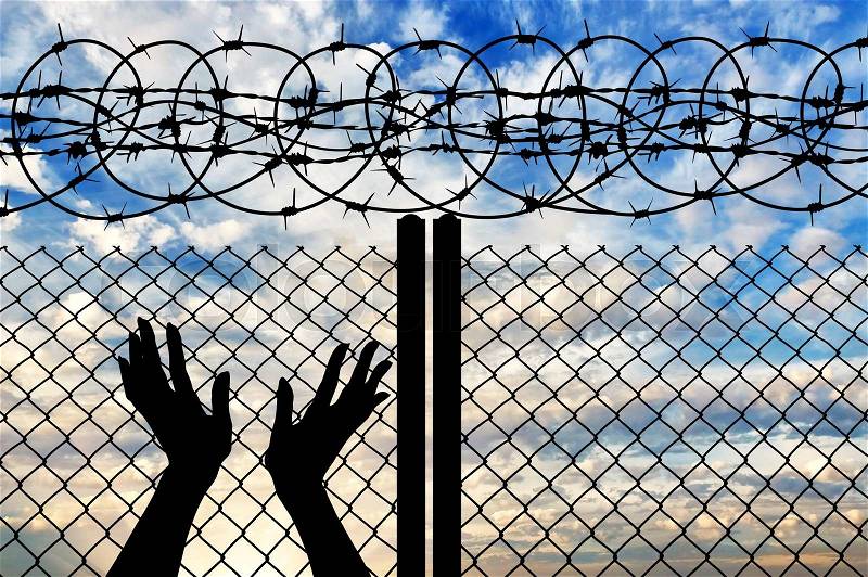 Concept of religion is Islam. Silhouette of hands facing the sky against a background of a fence with barbed wire , stock photo