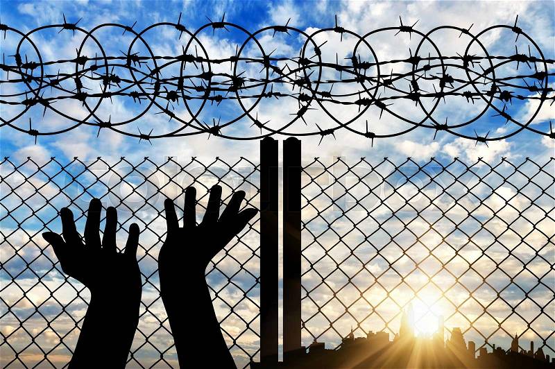 Concept of religion is Islam. Silhouette of hands facing the sky against a background of a fence with barbed wire and the city, stock photo