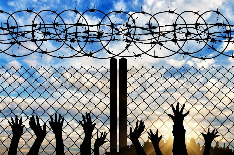 Concept of religion is Islam. Silhouette of hands facing the sky against a background of a fence with barbed wire and the city, stock photo