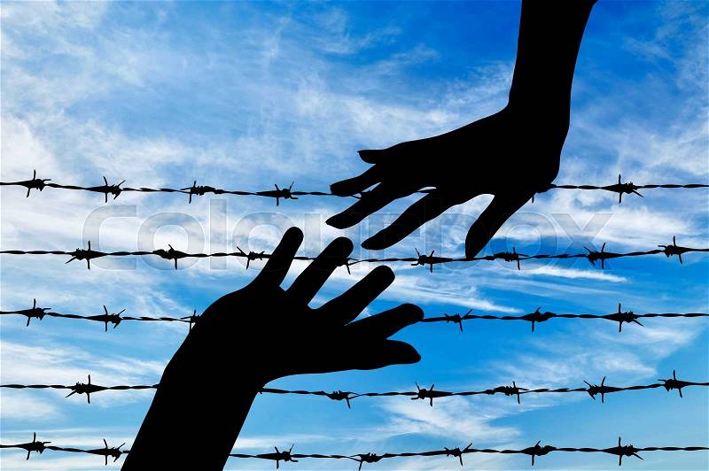 Concept of refugee. Silhouette helping hand to refugees on the background of the fence of barbed wire, stock photo