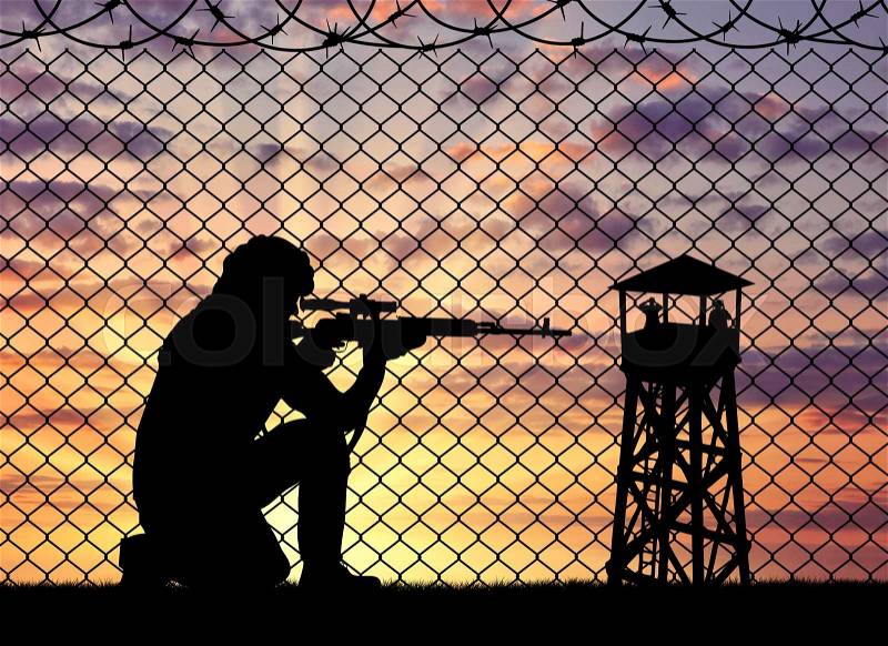 Concept of terrorism. Silhouette of a terrorist sniper near the border fence and watchtower at sunset, stock photo