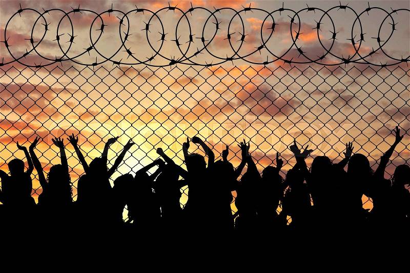 Concept of the refugees. Silhouette of a crowd of refugees at the border at sunset, stock photo