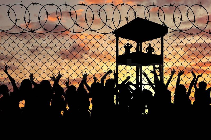 Concept of the refugees. Silhouette of a crowd of refugees at the border against the sunset and the guard tower, stock photo