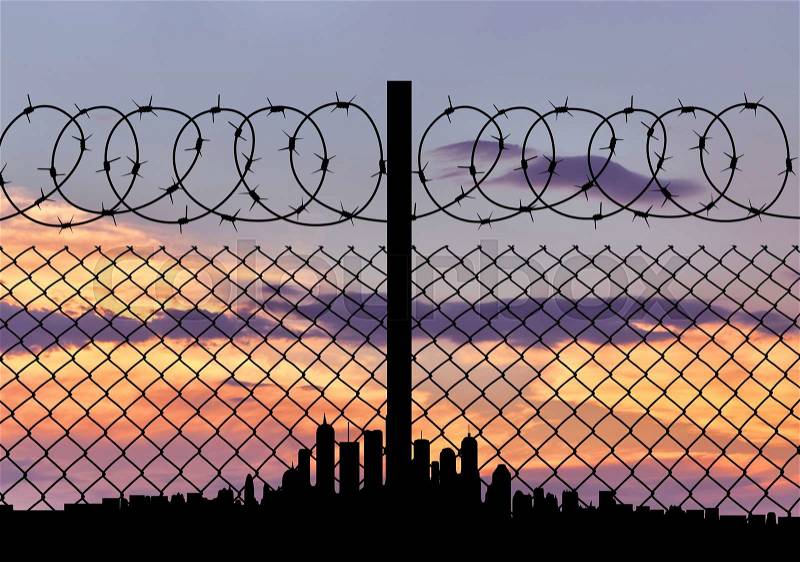 Concept of security. Silhouette of barbed wire fence on the background of the city away, stock photo