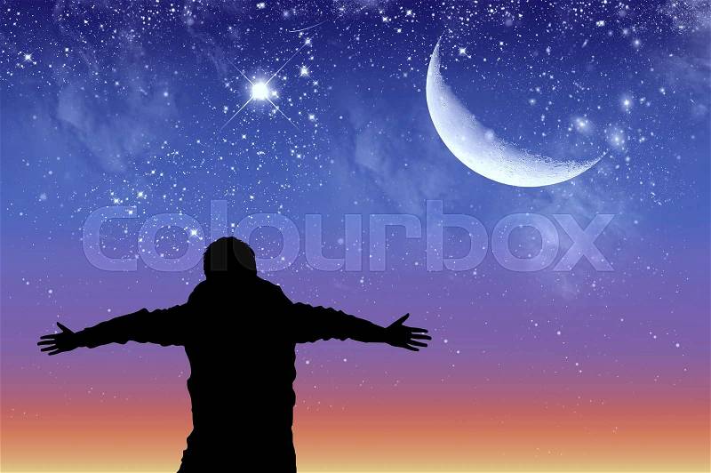 Concept of success. Silhouette of a happy man on the background of the starry sky and the moon, stock photo