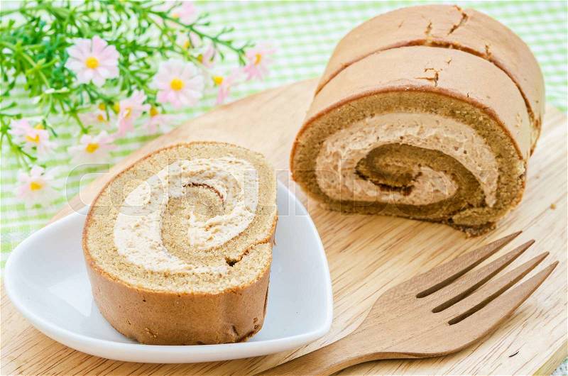 Coffee roll cake on plate, jam roll on tablecloth, stock photo