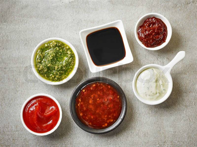 Bowls of various sauces on gray stone background, top view, stock photo