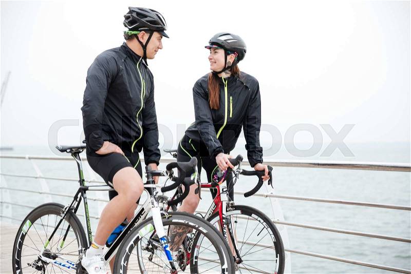 Happy couple on bicycle resting and flirting near sea, stock photo