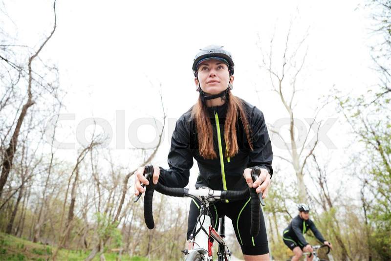 Concentrated young woman riding bike in park, stock photo