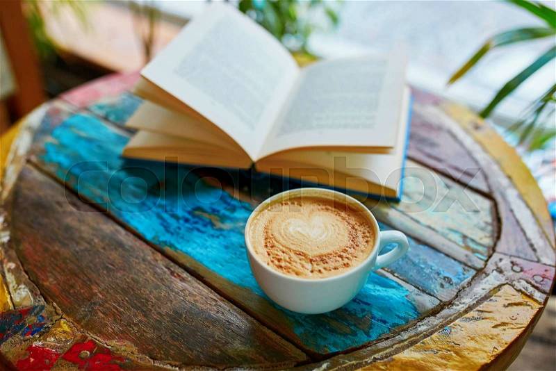 Cup of fresh coffee and book on a wooden table, stock photo