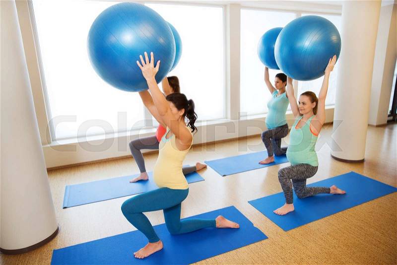 Pregnancy, sport, fitness, people and healthy lifestyle concept - group of happy pregnant women exercising with ball in gym, stock photo
