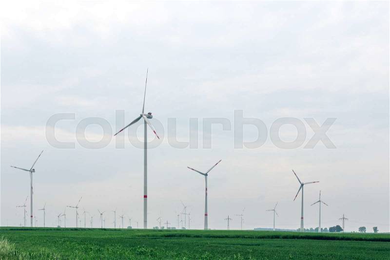 Ecological alternative power with windmill on the green field.Windmill generator in wide yard. Yard of windmill power generator under blue sky, shown as energy industry concept, stock photo