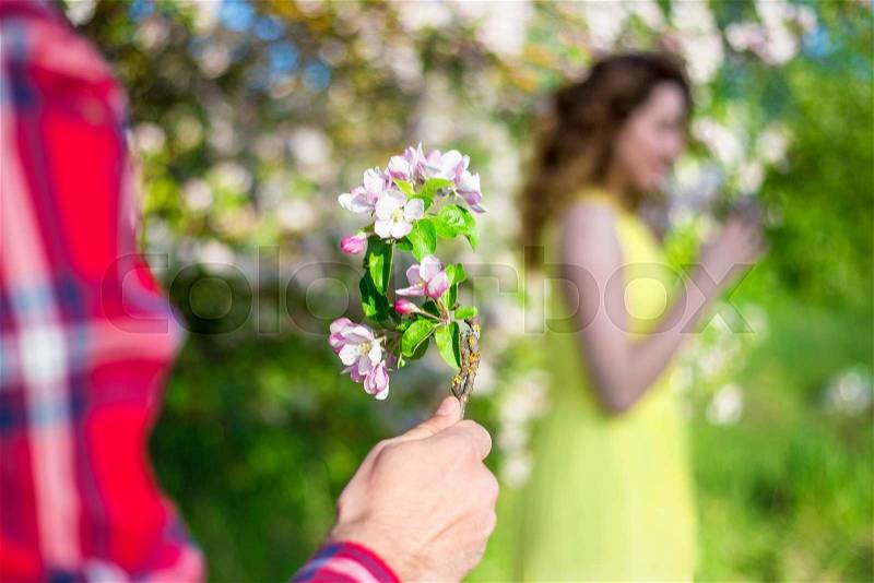 Man giving flowers to his girlfriend in summer garden, stock photo