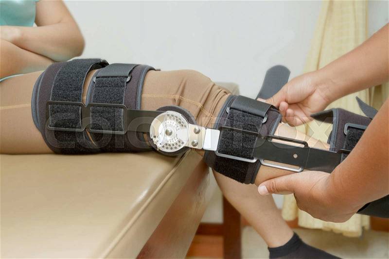 Orthopedist secures leg brace on knee, knee brace support for leg or knee injury, stock photo
