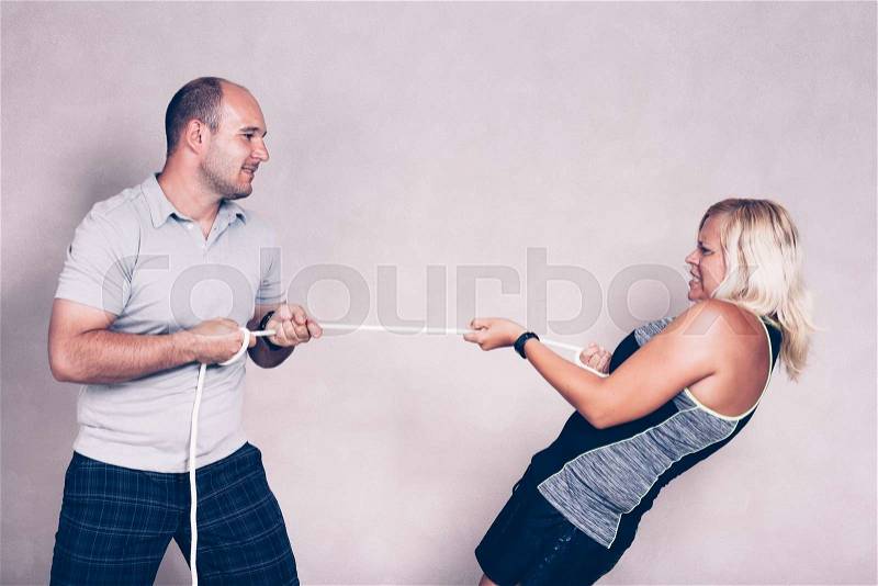 Man and determined sporty woman pulling a rope. Competition, determination and effort concept, stock photo