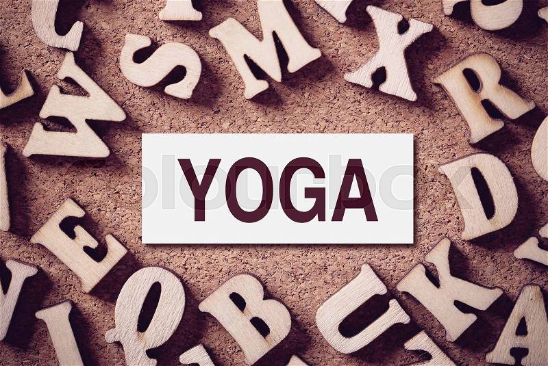 Corkboard covered with word Yoga and multiple wooden letters, stock photo
