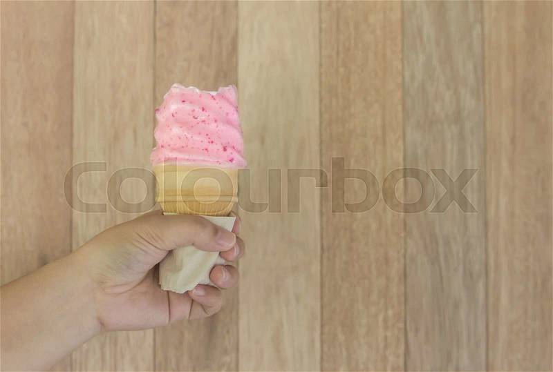Ice cream strawberry cone held up to the hot summer on wood background, stock photo