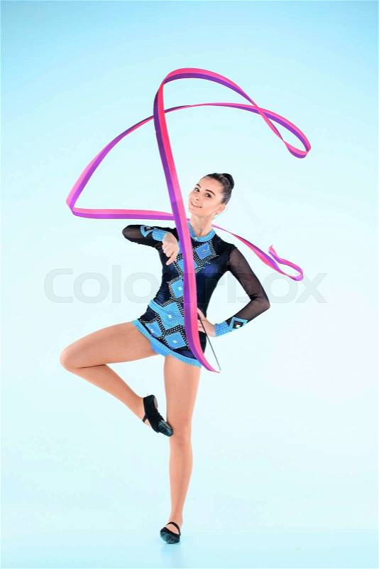 The girl doing gymnastics dance with colored ribbon on a blue background, stock photo