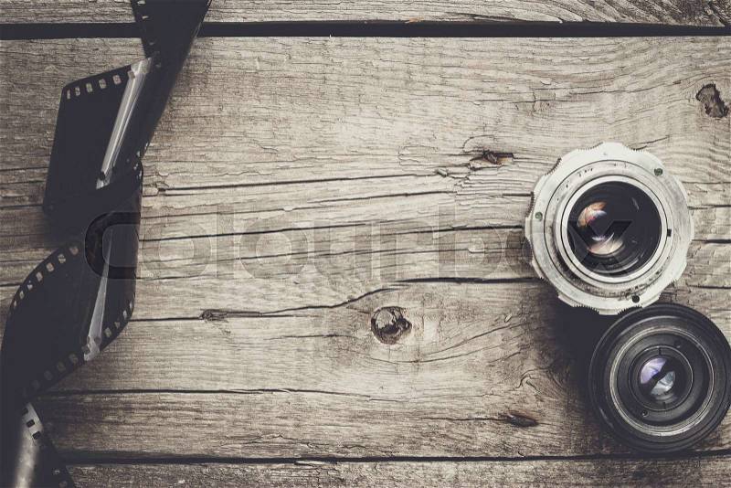 Retro camera lenses and negative film on wooden table, stock photo