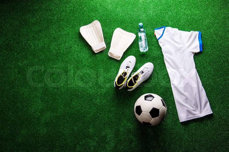 Soccer ball,cleats and various football stuff against artificial turf. Studio shot on green background. Copy space, stock photo