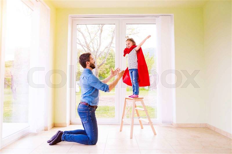 Hipster father with his cute little princess daughter jumping into his arms, wearing red cape, stock photo