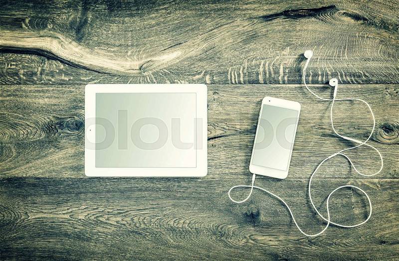 Digital devices. Smart phone with headphones and tablet pc. Vintage style toned picture, stock photo