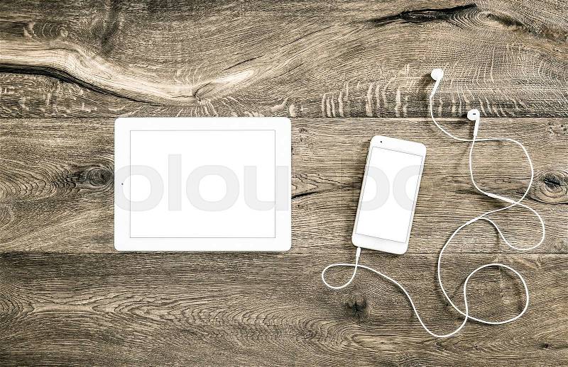 Mobile phone with headphones and tablet pc on office desk. Digital gadgets on wooden background. , stock photo