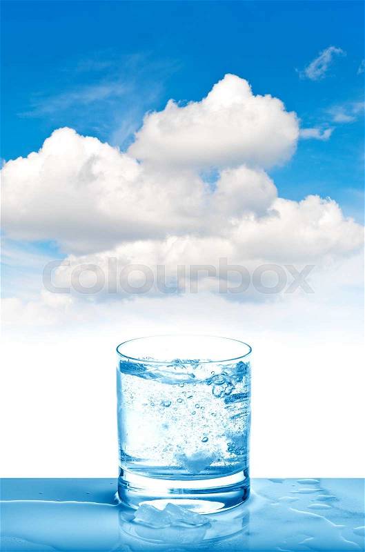 Sparkling water in glass on blue sky background. Fresh cold drink , stock photo