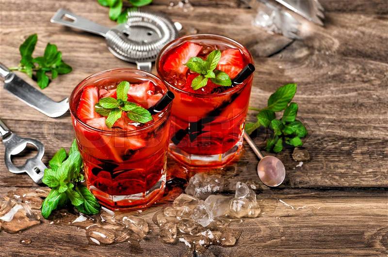 Red cocktail with ice, mint leaves and strawberry. Alcoholic and non alcoholic drinks making bar tools, stock photo