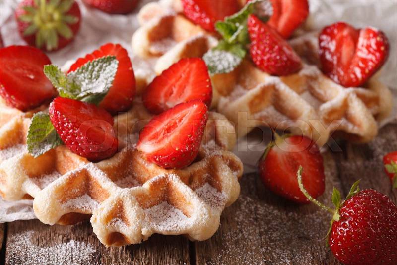 Belgian cuisine: waffles with strawberries, powdered sugar and mint on a table macro. horizontal , stock photo