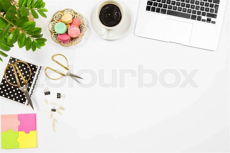 Feminine office desk workplace. Coffee, cookies, laptop computer and green plant on white table background. Top view. Flat lay, stock photo