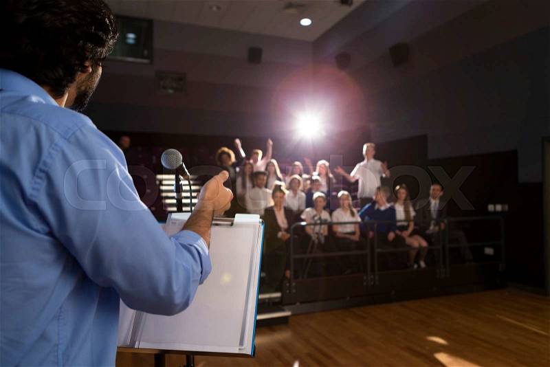 Male teacher giving a speech in a lecture hall to students and teachers. , stock photo