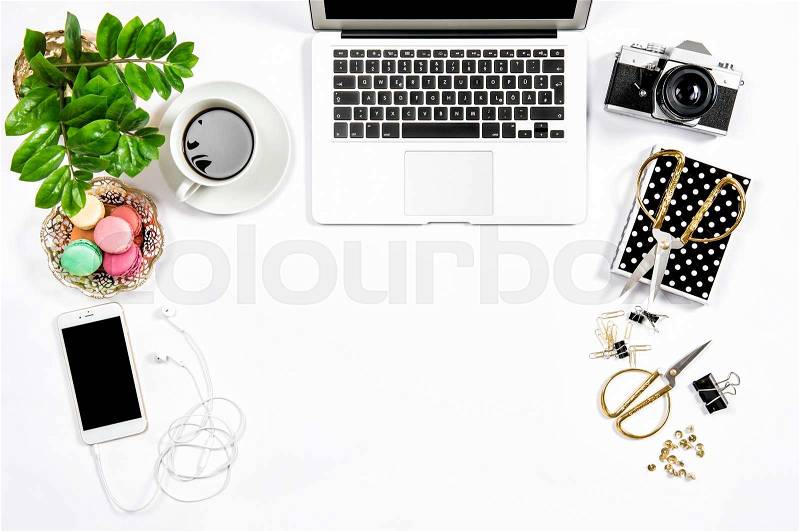 Feminine workplace still life. Coffee and macaroon cookies. Office supplies and laptop, stock photo